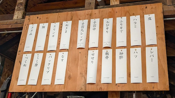 A wooden board with paper menu items attached to it