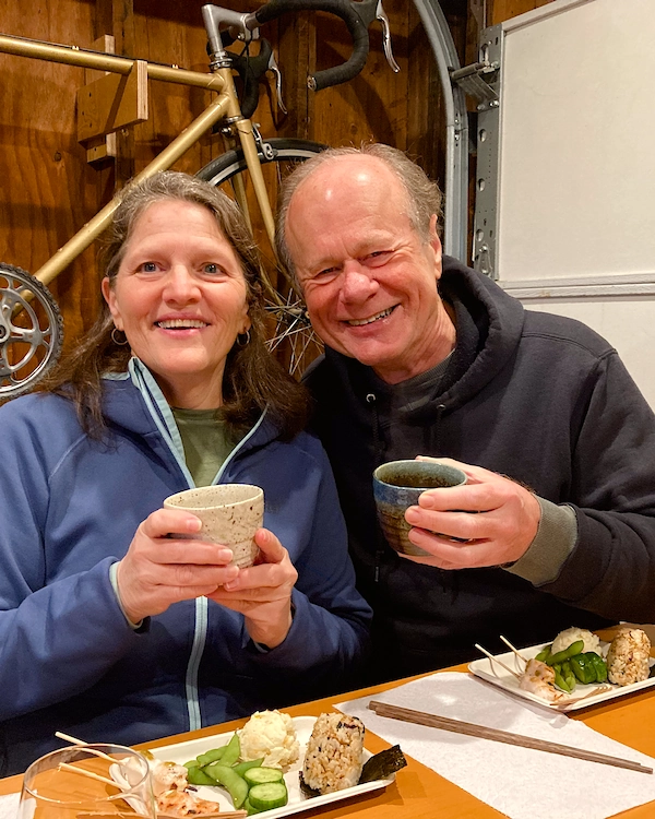 A man and woman smiling holding cups of soup