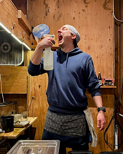 A man sprays sake into his mouth