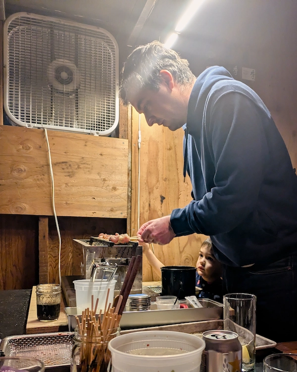 A man and small child grill skewers together