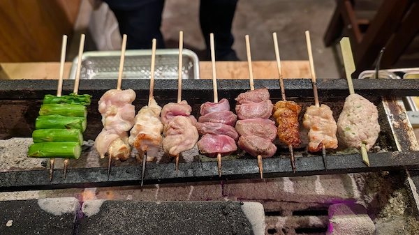 A variety of yakitori skewers grilling over charcoal
